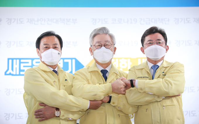 좌측부터 장현국 경기도의회 의장, 이재명 경기도지사, 박근철 민주당 대표의원이 경기도 지역화폐를 이용한 소비진작을 발표하고 서로간 손을 맞잡고 있다. 1천억 규모의 이번 정책을 통해 최대 1조원 상당의 경제효과가 예상되는 가운데, "땅을 파봐라. 5만원이 나오는지..."라는 보편적 경제 논리가 사실로 입증될지 귀추가 주목되고 있다. 