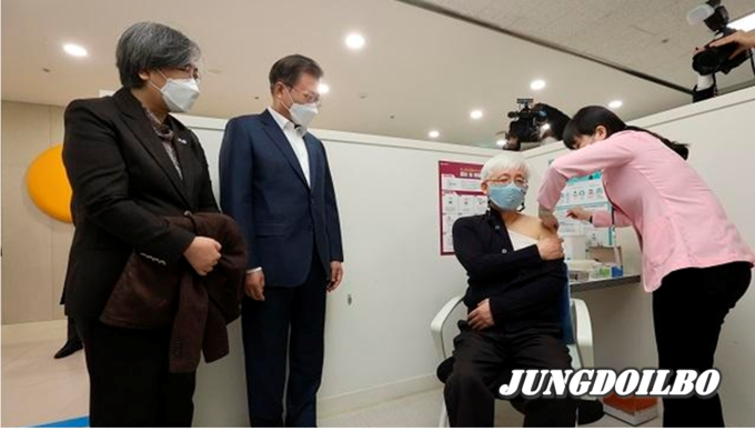 문재인 대통령과 정은경 질병관리청장이 26일 서울 마포구보건소를 방문, 재활시설 종사자인 김윤태 의사(푸르메 넥슨어린이 재활병원)가 아스트라제네카(AZ) 백신을 접종받는 모습을 지켜보고 있다