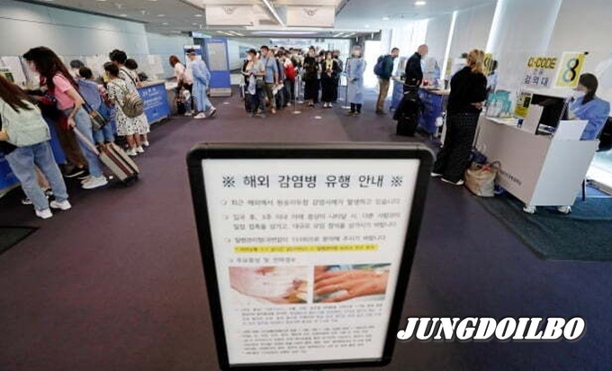 인천국제공항 제1터미널 입국장 승객들 앞에 원숭이두창 관련 안내문이 세워져 있다.