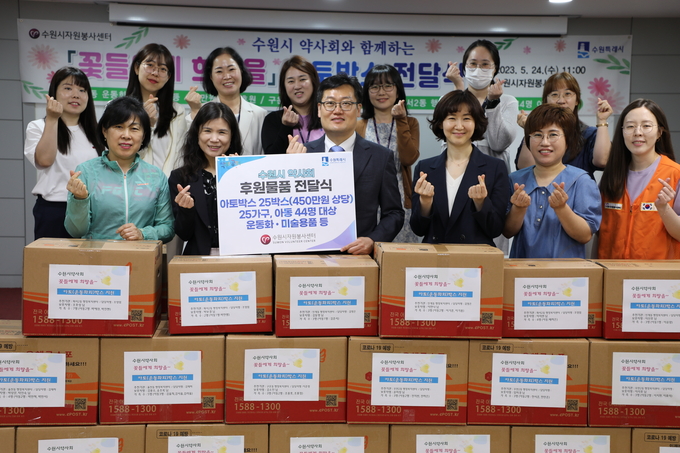 최영화(앞줄 왼쪽에서 두 번째) 수원시자원봉사센터장과 김호진(앞줄 왼쪽에서 세 번째) 수원시약사회장, 신지연(앞줄 오른쪽에서 세 번째) 수원시약사회 부회장 등이 24일 후원물품 전달식 후 율천동·화서2동 등 행정복지센터 관계자들과 기념 촬영을 하고 있다.