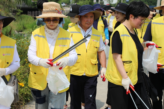 김현광(가운데) 수원문화재단 대표이사가 7개 공공기관 임직원, 자원봉사자들과 황구지천 길가에 버려진 쓰레기를 줍고 있다.