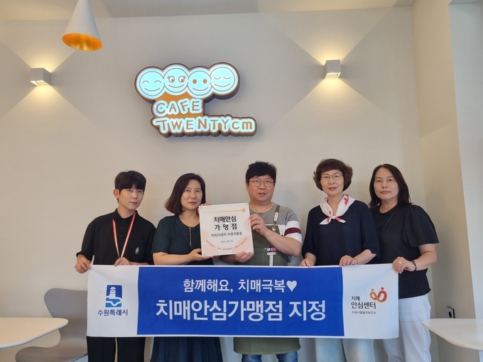 팔달구보건소 관계자가 커피20센치 수원지동점에 현판을 전달하고 있다.