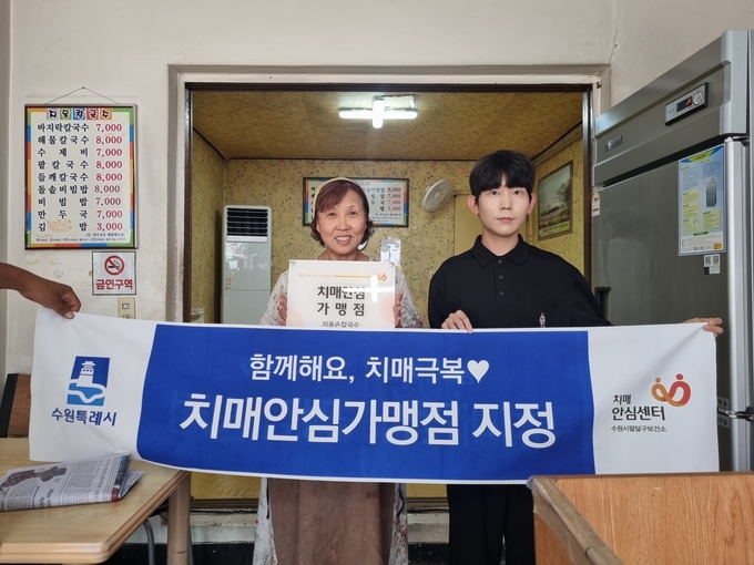 팔달구보건소 관계자가 지동손칼국수에 현판을 전달하고 있다.