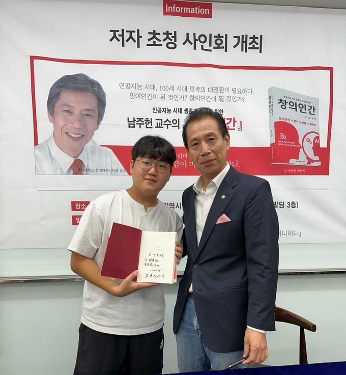 남주헌 교수가 저자 사인 후 김재홍 학생과 기념사진을 촬영하고 있다.