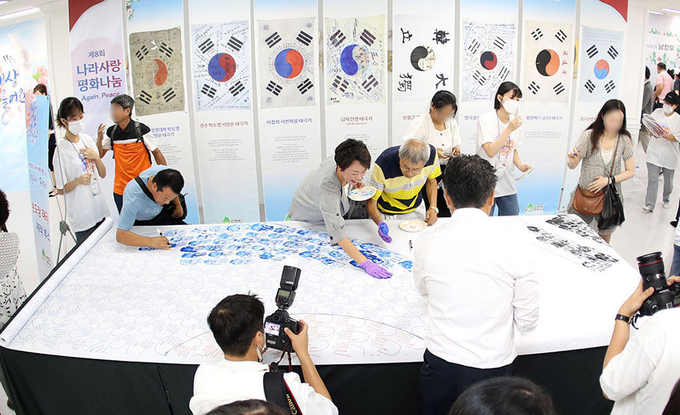 신천지자원봉사단 수원화성오산 지부에서 지난 19일 개최한 제8회 나라사랑 평화나눔 사전 행사장에서 시민들이 태극기에 손도장을 찍고 있다. 