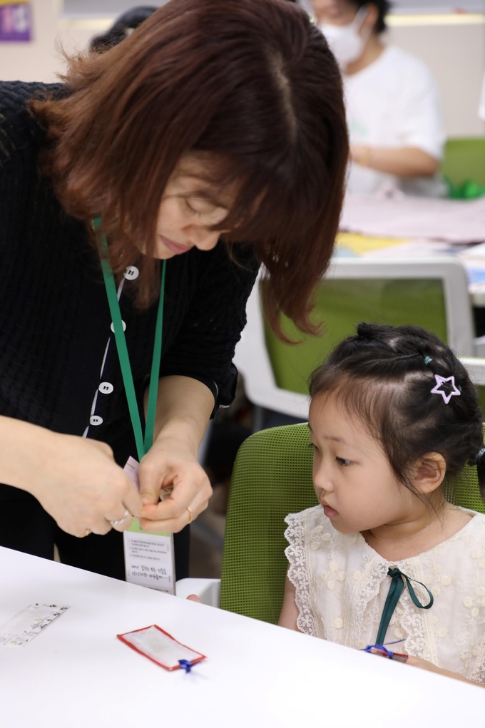 강사가 다문화 가족 아이에게 ‘한지 북아트’ 만들기를 도와주고 있다.
