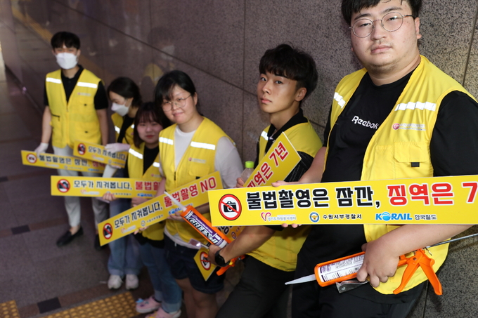 청년팀플 수원청년봉사단’이 수원역 6번 출구 계단에서 불법 촬영 예방 표찰을 부착한 뒤 기념 촬영을 하고 있다.
