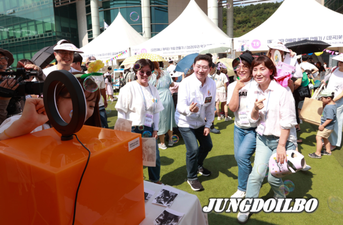 이상일 용인특례시장이 행사장에 마련된 도서관 별 체험 부스를 방문해 도서관 직원들과 스티커 사진을 찍고 있다.
