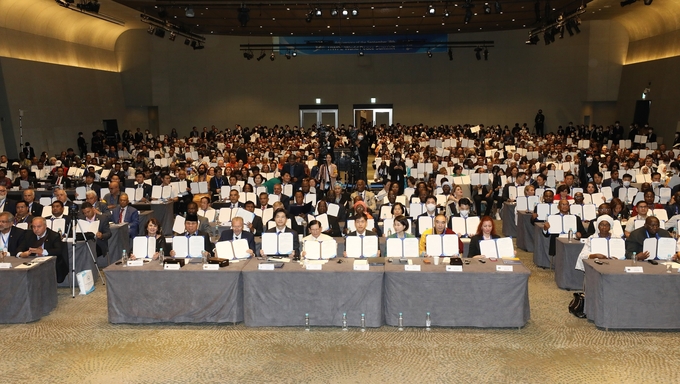 HWPL 9·18 평화 만국회의 9주년 기념식이 열린 가운데, 18일 오후 열린 '2023 평화 지도자 콘퍼런스'에서 참석자들이 직접 서명한 '세계평화를 위한 다짐서'를 들어 보이고 있다.