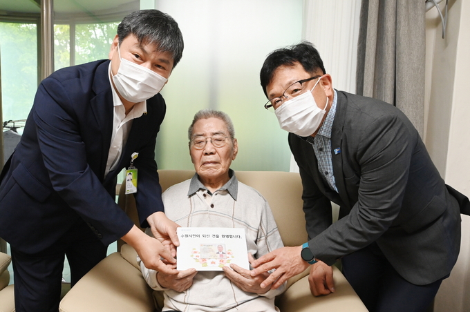 김현수 제1부시장(오른쪽)이 오성규 애국지사(가운데)에게 주민등록증을 전달하고 있다.
