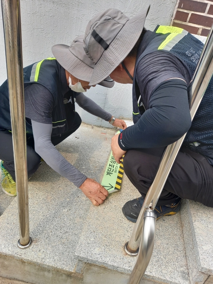 행궁동 경기행복마을지킴이들이 행궁동 지역 계단에 야광 안전 스티커를 시범 부착하고 있다.