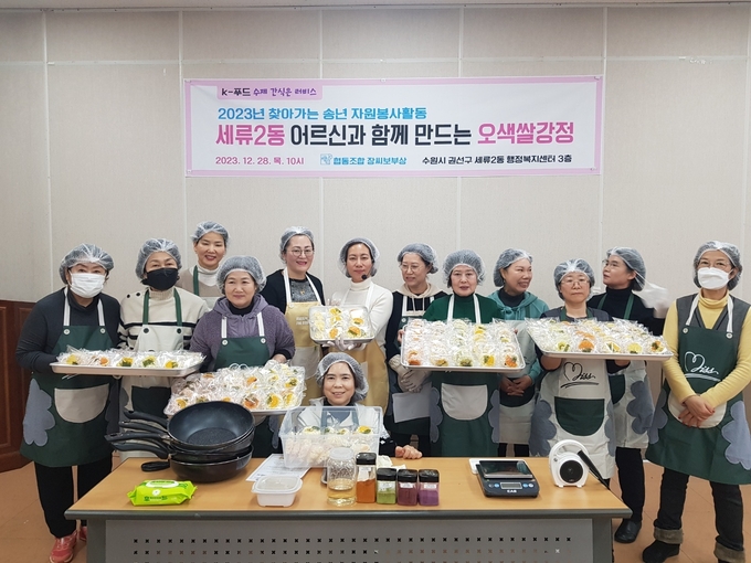 협동조합 장씨보부상은 12월 28일, 조합원들과 함께 수원 권선구 세류2동 행정복지센터 강의실에서 지역 어르신들을 모시고 쌀강정 체험 참석자들이 기념촬영을 하고 있다.