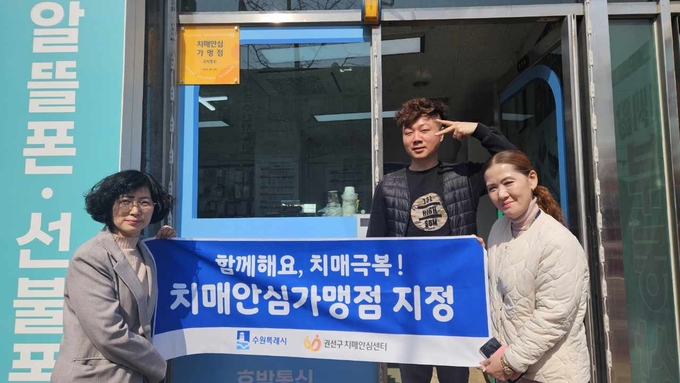 치매안심가맹점으로 지정한 호박통신에 현판을 전달하는 모습