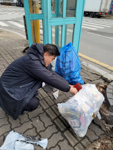 수원시 깨끗한 쓰레기처리 감시원이 무단 배출된 생활폐기물을 살펴보고 있다.