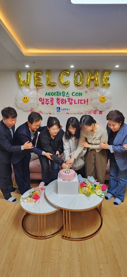 셰어하우스 6호 입주기념식에서 청년들과 참석자들이 케이크를 자르고 있다.