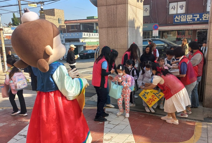 후문에서 선물을 나눠주는 학부모회, 운동회날 선물을 받고 즐거워하는 어린이들
