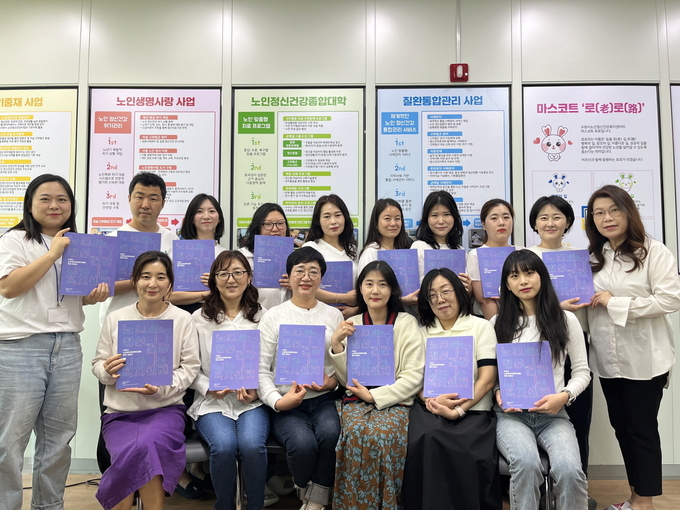 수원시노인정신건강복지센터 관계자들이 ‘노인건강관리 운영 지침서’를 들고 있다.