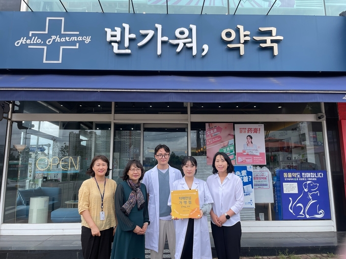 영통구치매안심센터 관계자가 반가워, 약국에 현판을 전달하고, 기념사진을 촬영하고 있다.