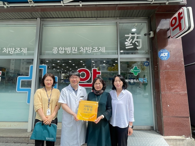 영통구치매안심센터 관계자가 에이플러스약국에 현판을 전달하고, 기념사진을 촬영하고 있다.