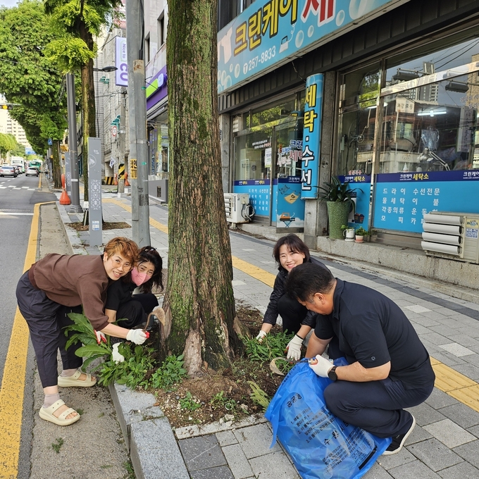 가로수 주변 풀뽑기 작업하는 봉사자들의 밝고 환한 모습