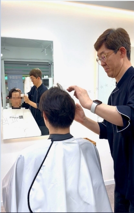 봉사 참여 이발소가 군 입영예정자에게 무료로 이발을 하고 있다.