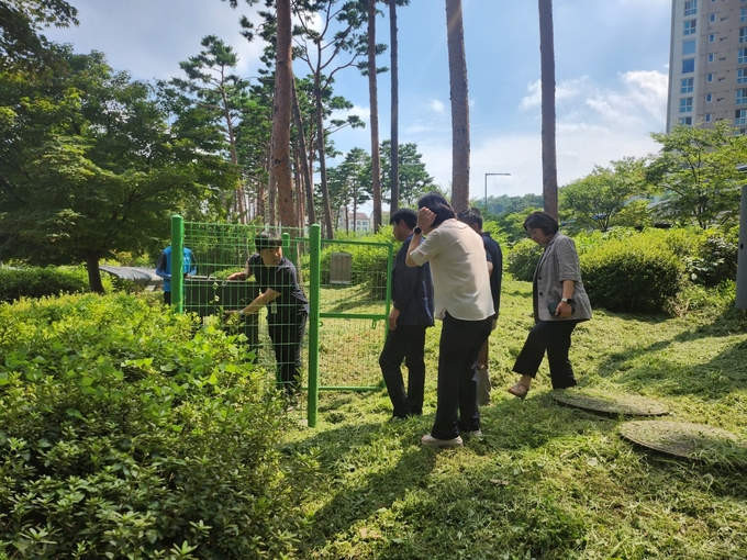 관계자들이 광교호수공원 가족캠핑장에 설치된 원격 모기감시 장치를 살펴보고 있다.