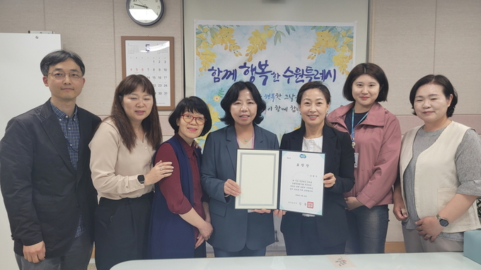 김은주 수원시 여성가족국장(오른쪽 3번째)과 직원들이 표창장을 들고 기념촬영을 하고 있다.