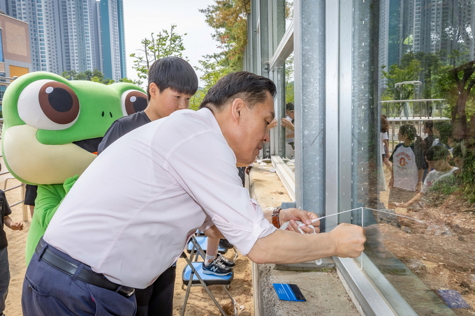 이재준 수원시장이 송림초등학교 학생들과 함께 야생조류 충돌방지 테이프를 붙이고 있다.