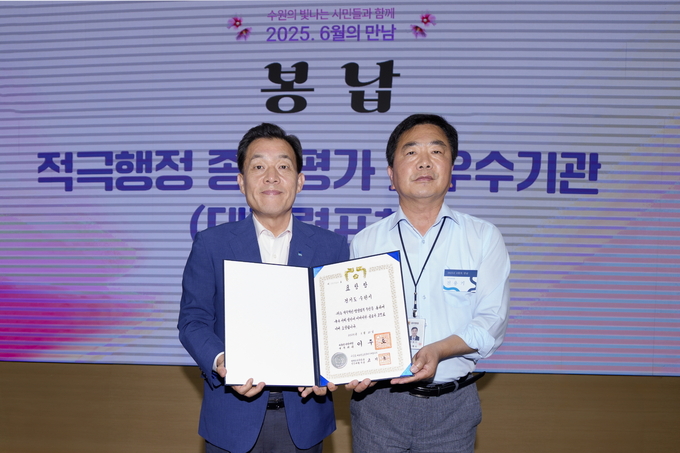 전용기 수원시 법무담당관이 9일 시청 중회의실에서 열린 ‘6월의 만남’ 행사 중에 이재준 수원시장(왼쪽)에게 대통령 표창을 봉납하고 있다.