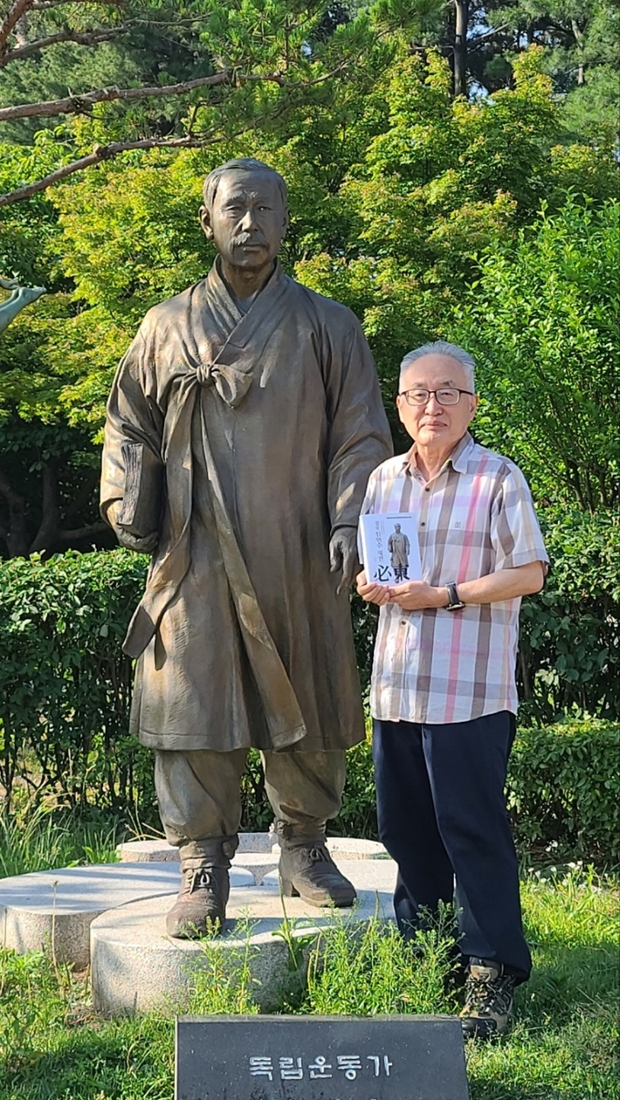 박환 이사장이 수원올림픽공원 필동 임면수 선생 동상에서 ‘필동 임면수 평전’을 헌정한 뒤 기념 촬영을 하고 있다.