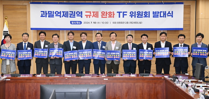 지난해 7월 국회에서 열린 ‘과밀억제권역 규제완화 TF 위원회 발대식’에서 참석자들이 과밀억제권역 완화를 위한 손팻말을 들고 있다.