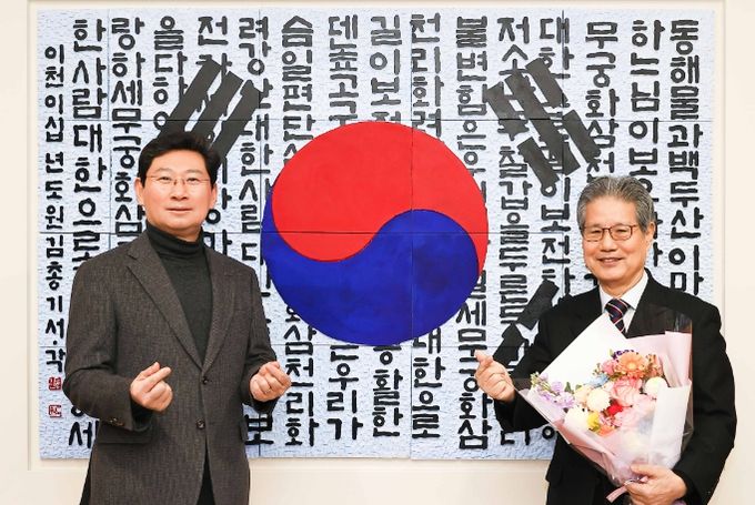 태극기와 애국가 가사를 담은 서각 작품을 용인특례시에 기증한 김총기 작가(오른쪽)가 이상일 시장과 24일 열린 작품 제막식에서 기념촬영을 하고 있다.