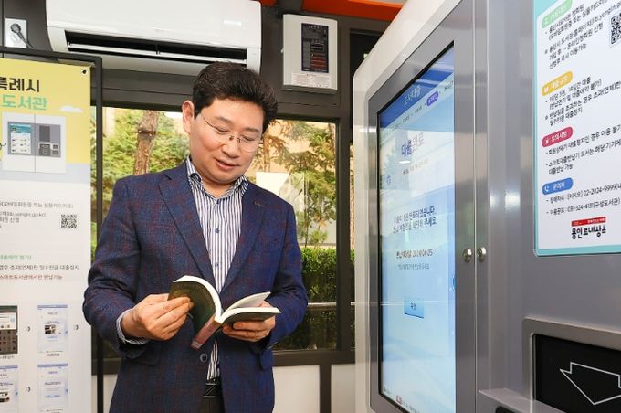 이상일 용인특례시장이 지난 11일 기흥구 상갈동 행정복지센터 1층 야외 부스에서 열린 스마트도서관 11호점 개관식에서 도서 대출을 해보고 있다.