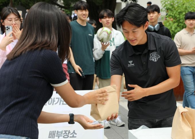 지난해 6월 8일 아주대학교에서 열린 ‘찾아가는 밥차’에서 수원FC 이승우 선수가 청년들에게 햄버거를 건네주는 장면.